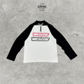WE11DONE white quarter-zip top with black raglan sleeves and stacked pink and black chest logos.