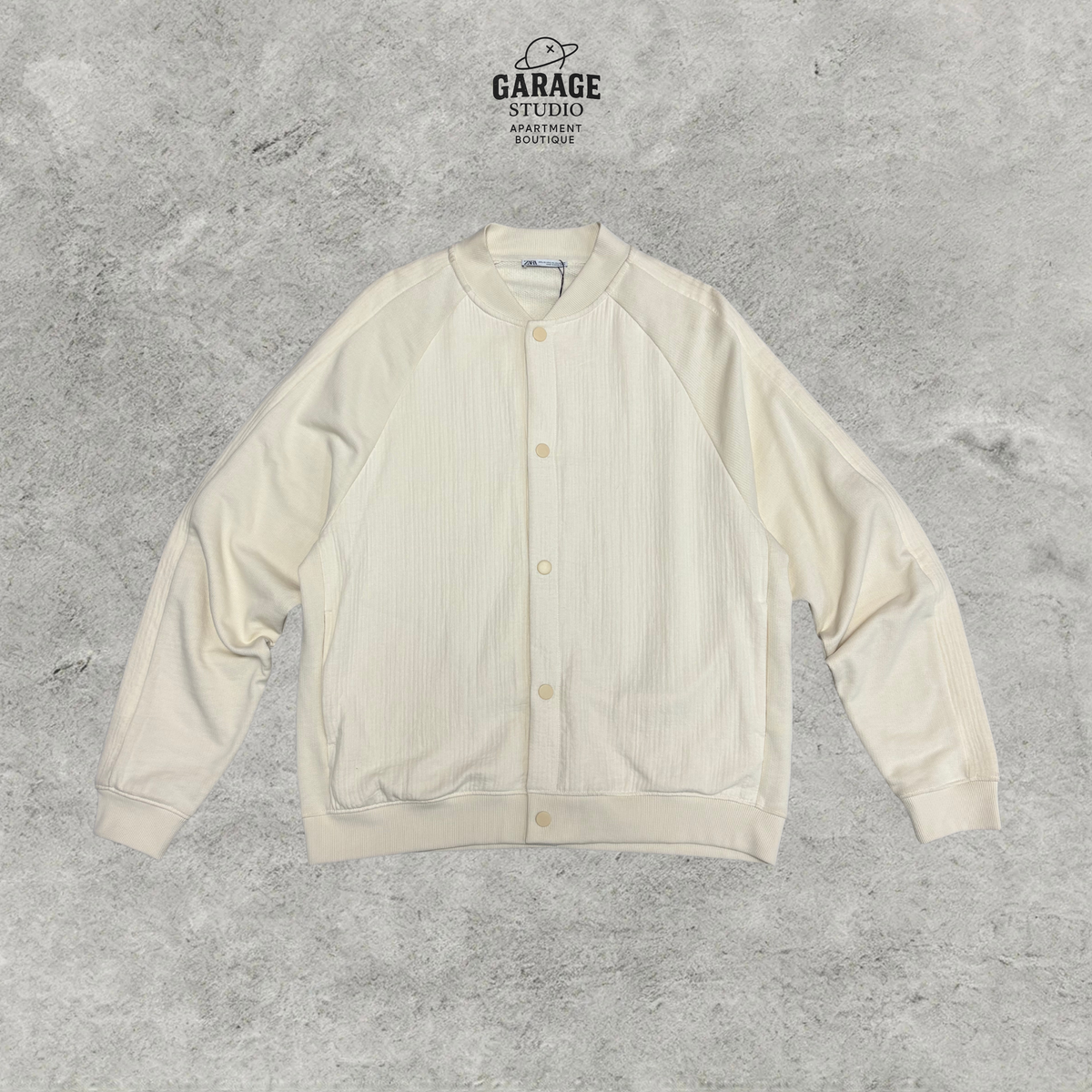 Cream textured bomber-style jacket with tonal button front, raglan sleeves and ribbed trims