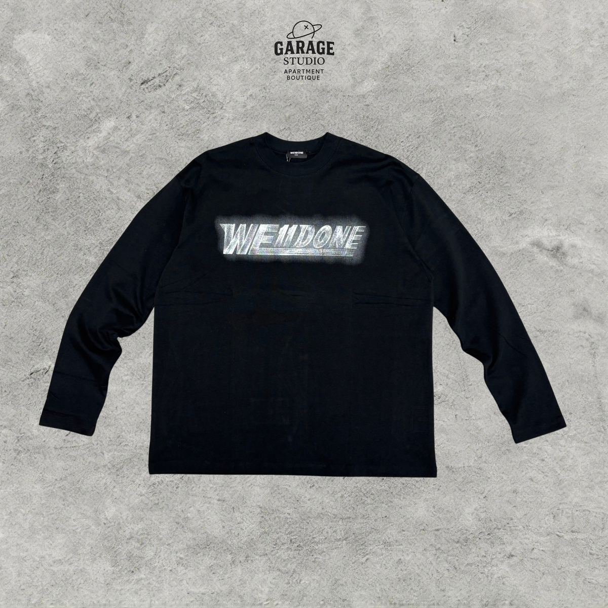 Front of black WE11DONE long-sleeve crew-neck T-shirt with a light-coloured chest logo graphic.